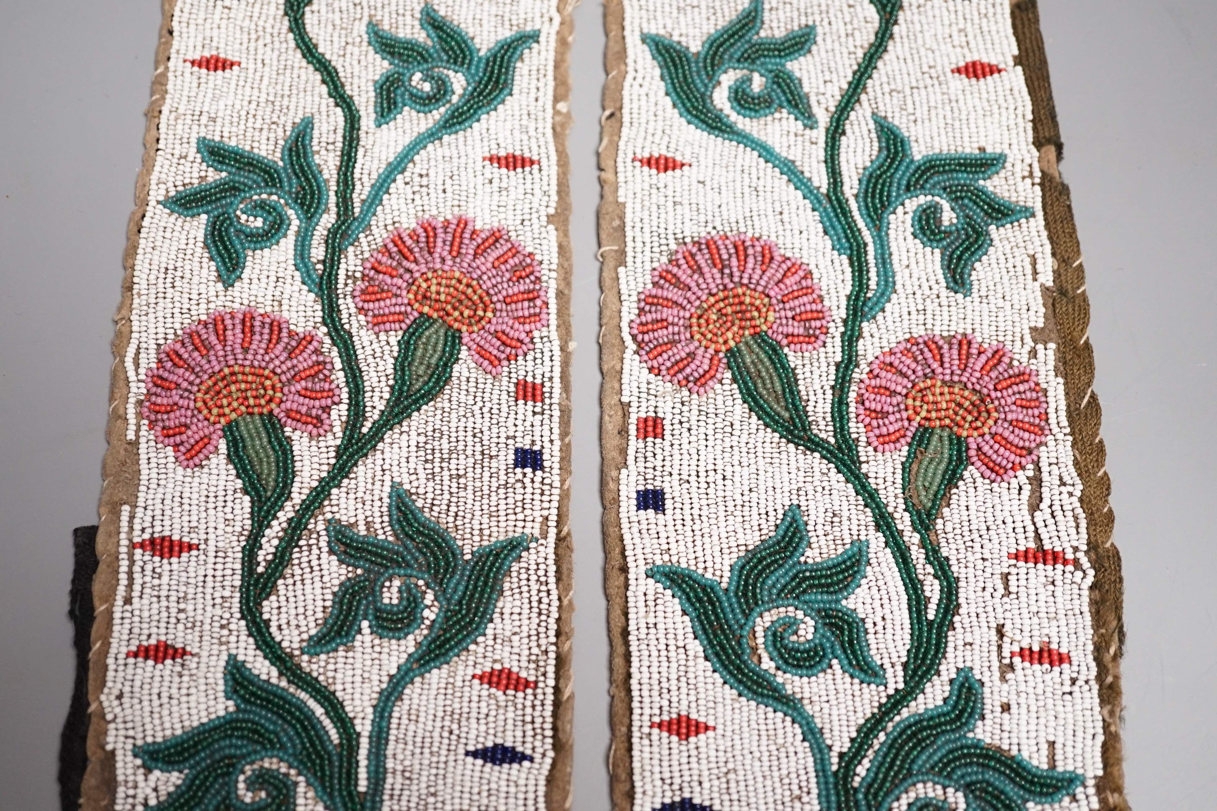 A fine pair of Native American Plains Indian rectangular beadwork panels, with floral designs and tribal markings, leather backing with remains of fabric edges, length 30cms